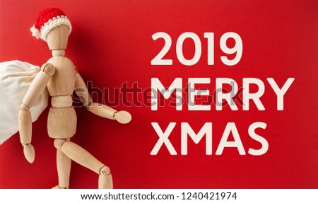 holiday and design concept - wooden mannequin red hat and gift bag like santa claus hold empty red board isolated on white background