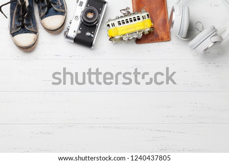 Travel vacation background concept with camera, passport, headphones and tram toy on wooden backdrop. Top view with copy space. Flat lay