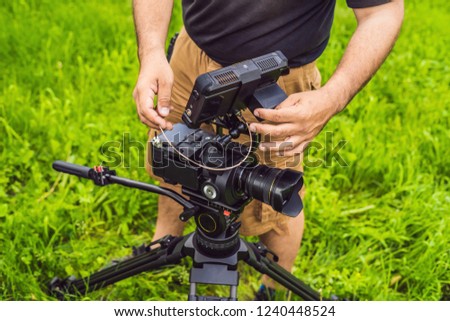a professional cameraman prepares a camera and a tripod before shooting