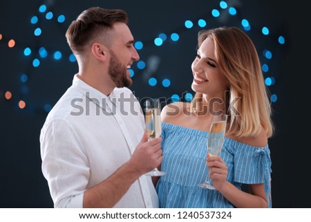 Happy couple with champagne in glasses on blurred background
