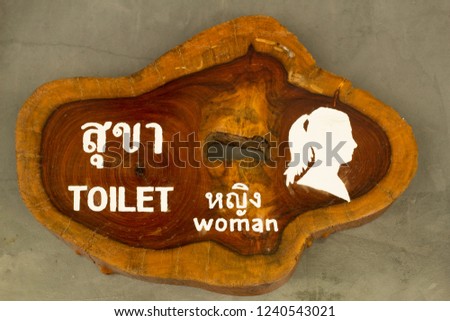 Public toilet. Wooden sign on the cement wall at the bathroom. Vintage wood sign