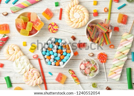 Many different yummy candies on white wooden background, top view