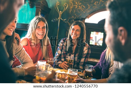 Group of happy friends drinking beer at brewery bar restaurant - Friendship concept with young millenial people enjoying time together having fun vintage pub - Focus right woman - High iso image