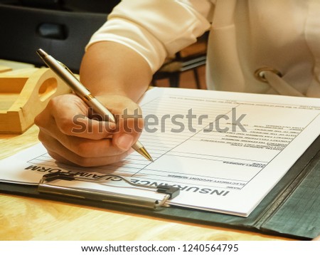 The human hand is filling information on the insurance claim form,
