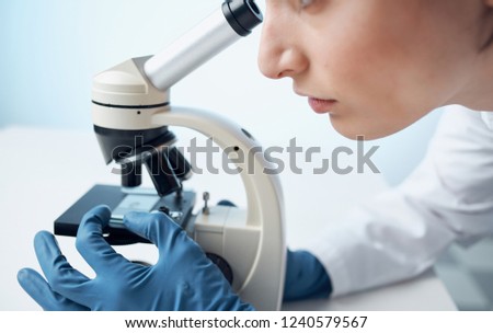 research woman with microscope and blue gloves                      