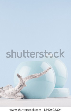 Modern minimalist in interior - blue smooth vases and shabby grey twig on white wooden table and light blue wall, vertical.