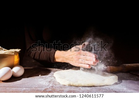 Female hands knead the dough on the table