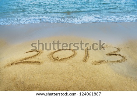Year 2013 hand written on the white sand in front of the sea Royalty-Free Stock Photo #124061887