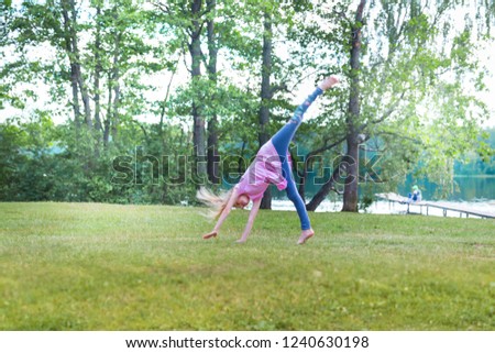Little blonde girl turning cartwhell outdoors on field