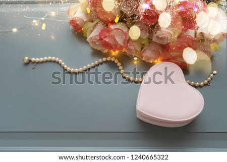 Rose fresh flowers bouquet with heart gift box on gray table from above, flat lay scene with bokeh lights