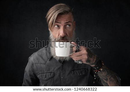 Portrait of a bearded man with a cup of coffee isolated on a black background