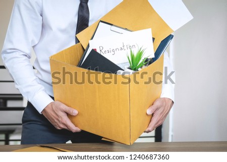 Businessman sending letter will being resignation and carrying packing belongings company and files into brown cardboard box, changing and resigning from work concept.