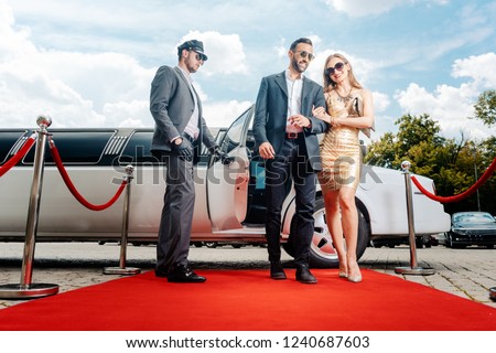 Couple arriving with limousine walking red carpet, a driver is opening the car door Royalty-Free Stock Photo #1240687603