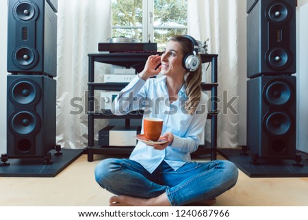 Woman listening to music from a Hi-Fi stereo at home Royalty-Free Stock Photo #1240687966
