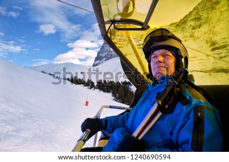 Portrait of  alpine skier in blue jacket  riding in cable car with mountains on the background. Swiss Alps. Grindelwald ski resort.
