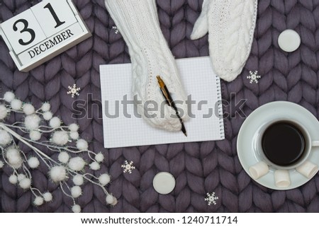 A background with Christmas decorations. A woman in knitted mittens is writing a letter for Santa.Xmas card.New Year, holidays concept.