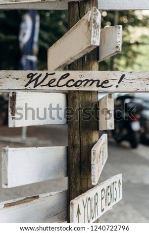 Wooden sign on the street - Welcome. Blurred street in the background.
