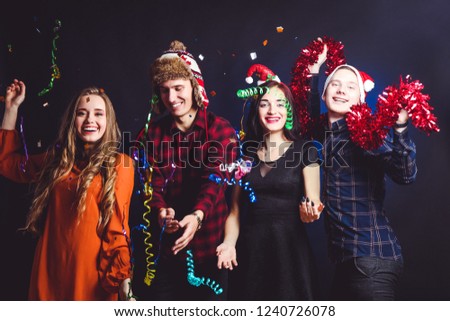 Cheerful company of friends, firecrackers and confetti on black background. Concept New Year.
