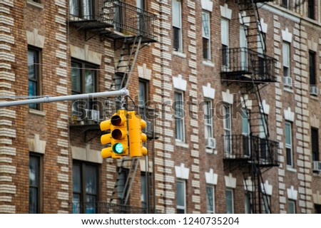 Close-up view of a traffic light and some buildings on background with windows and emergency stairs. Bronx District, New York, USA.