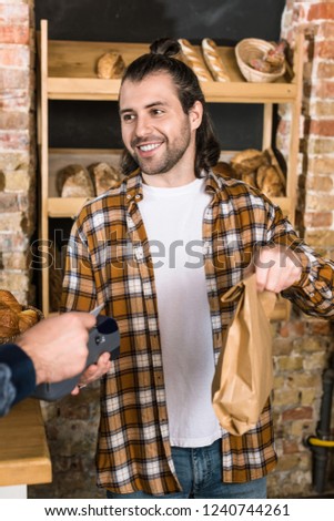 Customer paying by credit card and male seller holding paper bag