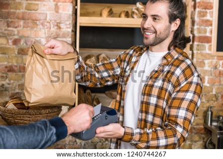 Customer paying by credit card and seller holding paper bag