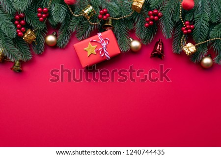 Christmas background concept. Top view of Christmas gift box red balls with spruce branches, pine cones, red berries and bell on red background.
