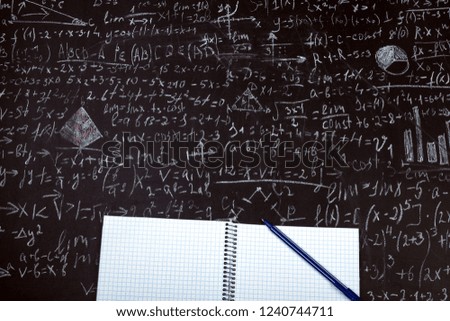 clean student notebook with a pen on the background of the board with examples and formulas