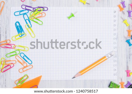 a sheet of paper in a cage, with a simple pencil for notes, surrounded by multicolored paper clips and buttons