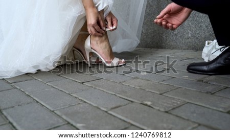 Young husband helping bride to wear dress sandals, comfortable shoes for events