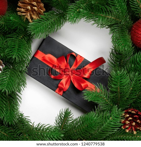 Christmas decoration. Christmas tree branches with gift box on white background. Round wreath fir with new year toy balls and fir cones. Top view.