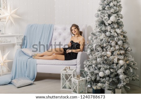 Very beautiful and gentle woman posing on the sofa in the New Year's interior