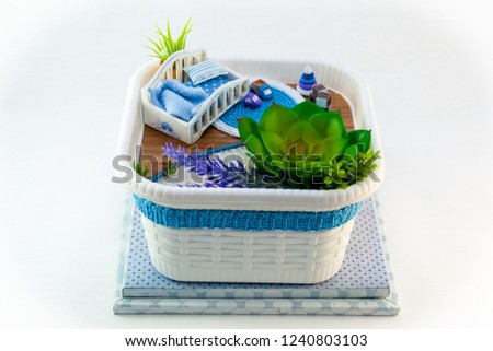 Hand Maid, a hobby blue toy room with a cot for baby, cubes and a car on the rug. The room also has flowers on the white sand.