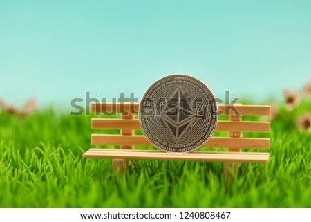 Ether coin on bench in garden as investment concept