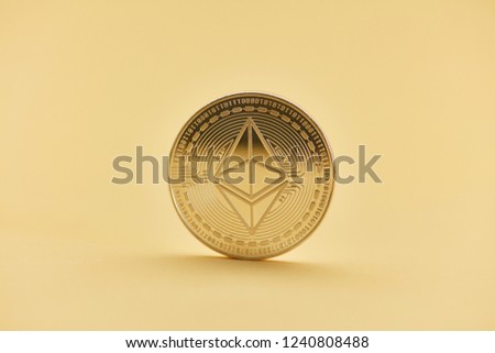 Ether coin against a yellow background with copy space