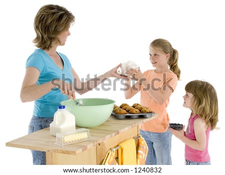 Mother and two girls baking muffins. Shot in studio over white.