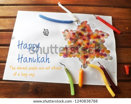 crafts for children to hanukah. Star of David made of dripping Chanukah candles. Text: Happy Chanukah. The eternal people are not afraid of a long way. Used Hanukkah candles, paper, dripping, wood