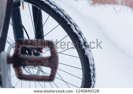 Bike in winter. Bicycle wheel on snow-covered road background.