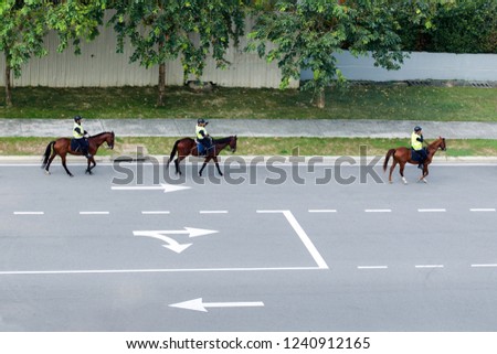 Mounted police on highway. Road marking indicating direction of movement. Traffic management, monitoring of chaperoning, eco-friendly transport. Malaysia.