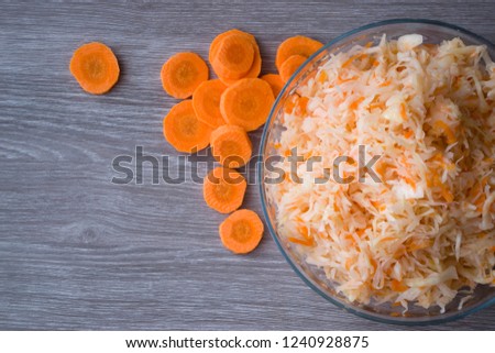 Salted chopped cabbage with carrots in a Cup on a wooden background. Fermented vegetables.