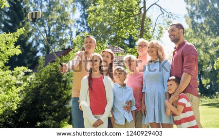 generation and people concept - happy family taking picture with smartphone and selfie stick in summer garden