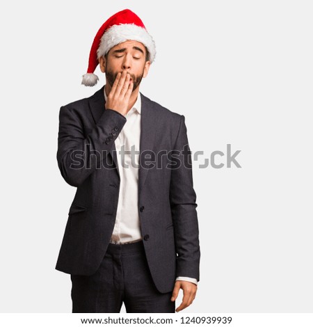 Young business man wearing santa hat tired and very sleepy