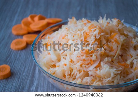 Orange carrot pieces and Salted chopped cabbage with carrots in a Cup on a wooden background. Fermented vegetables.