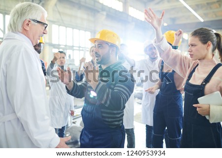 Portrait of female factory worker talking to mature manager during strike on industrial plant, copy space
