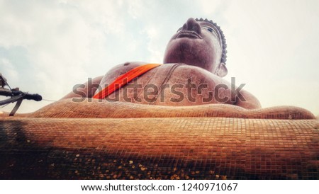 Big Buddha statue made of cement and covered with brown tiles.