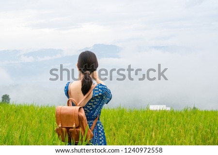 Beautiful young Asian woman with leather bag is taking landscape photo or selfie by smartphone  in rice field  at top of mountain ,countryside, Chiang Mai ,Thailand .Travel and social network concept