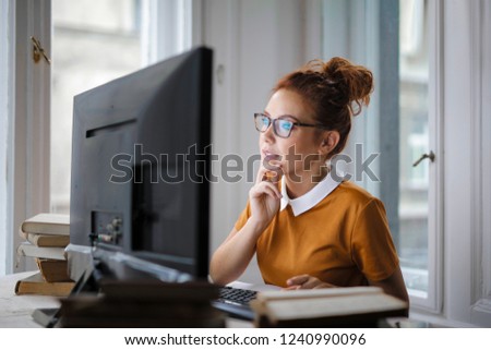 Young woman thinking in front of a computer.