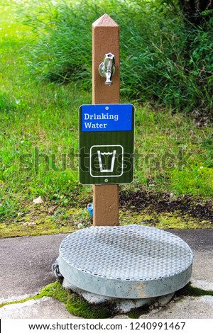 A drinking water sign next to a well cover