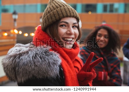Image of a happy young friends talking with each other utdoors winter concept.
