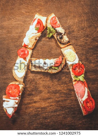 alphabet  letter - A from sandwiches with sausage, tomatoes and egg.  on dark wooden background