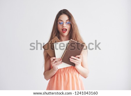 Education concept. Photo of young woman in the glasses and red lips holding the books.